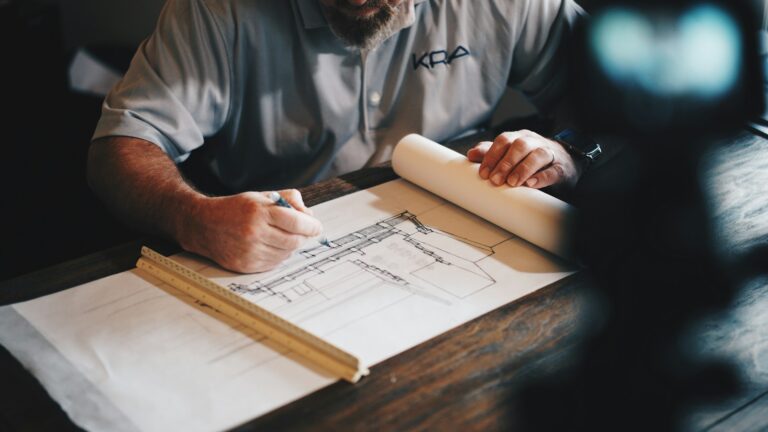 Person works on home remodel plans with ruler and pencil